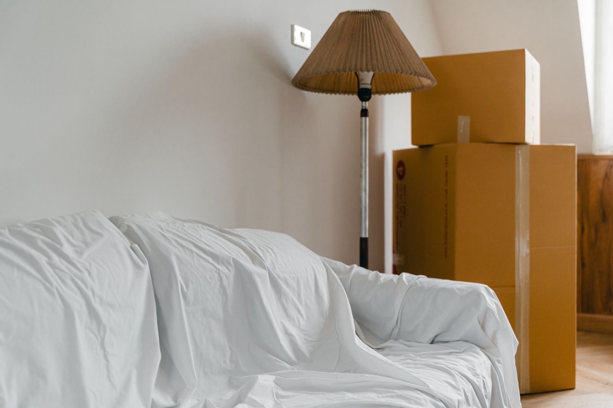 Living room prepared for moving with covered furniture and boxes